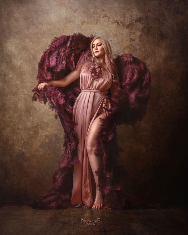 Blond woman in pink dress with wine colored angel wings