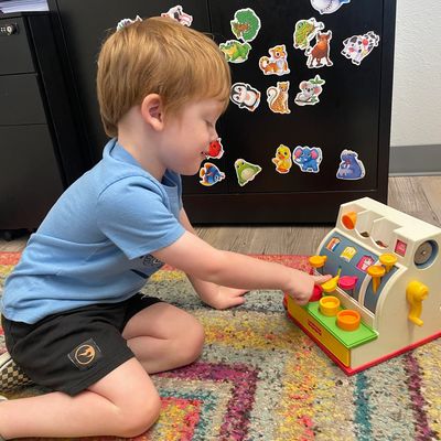 Child playing with toy cash register during speech therapy