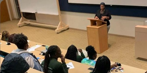 A speaker presenting to an audience in a lecture hall.
