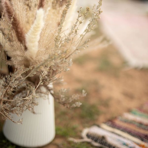 Dried floral arrangement in a white vase.