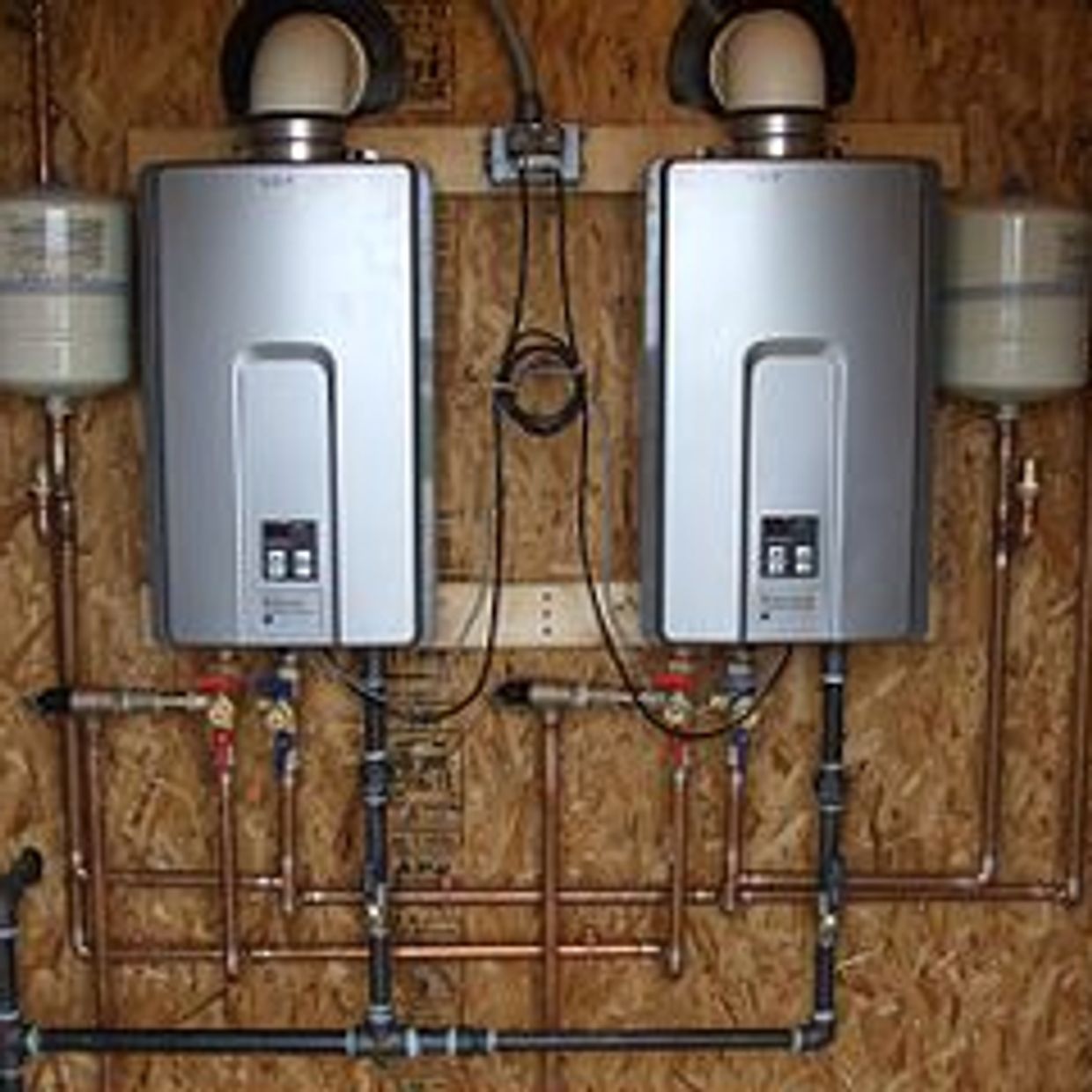 tankless hot water heaters installed on wooden interior wall with copper pipes