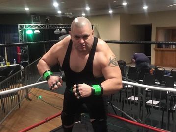 A wrestler posing aggressively in a boxing ring.