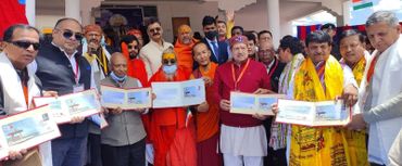 Group of people holding and displaying commemorative envelopes together outdoors.