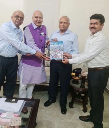 Four men holding a Himalaya Pariwar magazine together in a room.