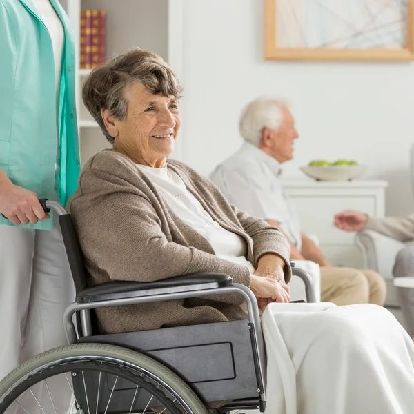 A carer moving an elderly woman with a wheel chair
