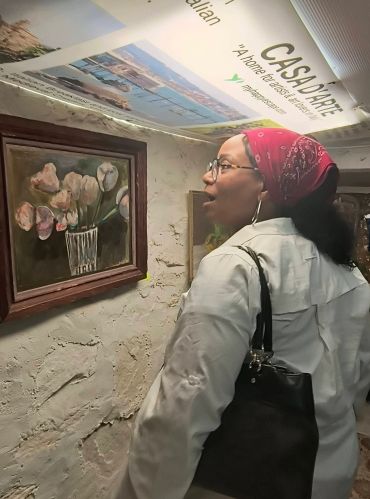 Woman observing a flower painting in a gallery.