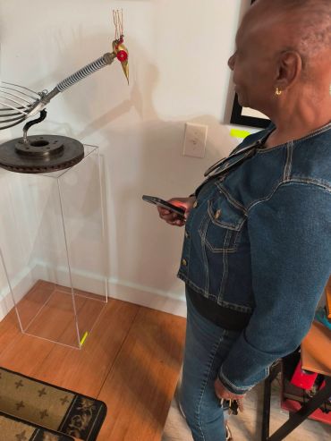 Woman observing a metallic bird sculpture on a stand.