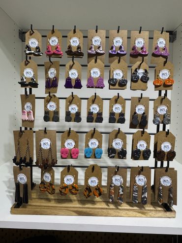 Colorful Halloween-themed earrings displayed on a rack with various spooky designs.