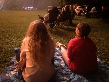 Two girls watching fireworks display at the activity field on the 4th of July
