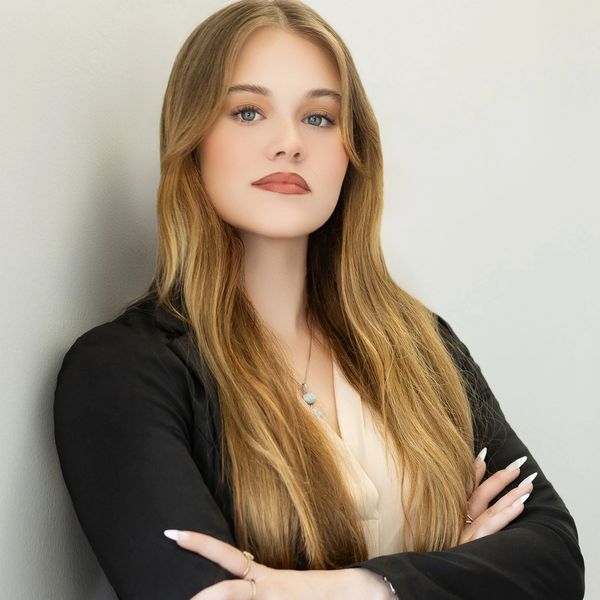 Confident young woman with long blonde hair crossing arms.