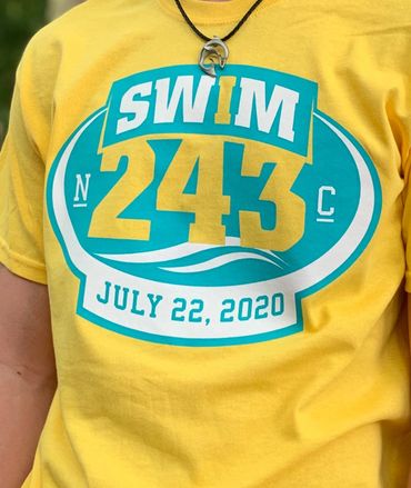 Photo of a person wearing a yellow t-shirt with a logo, center chest, that says SWIM243.