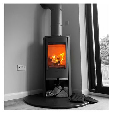 Modern wood-burning stove with bright flames inside, set in a cozy corner.
