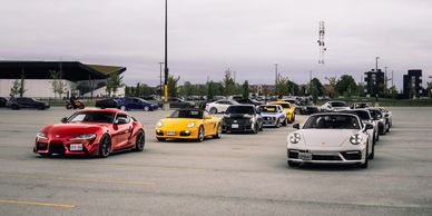 A lineup of sports cars parked in an outdoor lot under a cloudy sky.