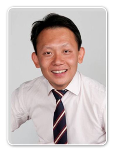 Smiling man in white shirt and striped tie against plain background.