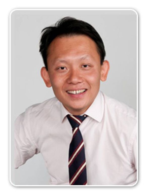 Man in a white shirt and striped tie smiling at the camera.