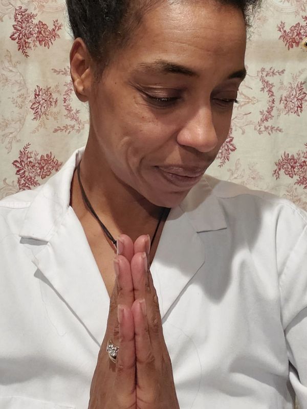 Person with hands in prayer position and eyes closed.