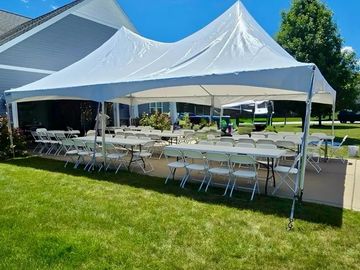 White event tent with tables and chairs on a lawn.