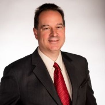 Professional man in suit with red tie posing for portrait.
