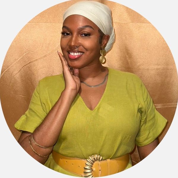 Smiling woman in a green top and white headscarf posing confidently.