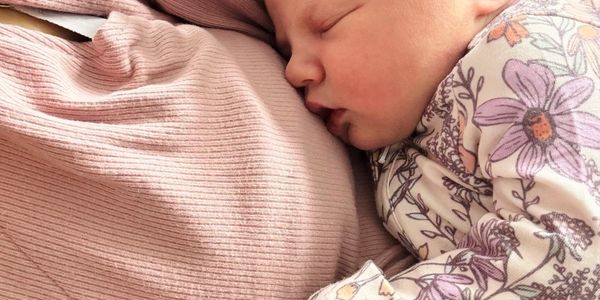 Newborn baby peacefully sleeping beside a pregnant belly.