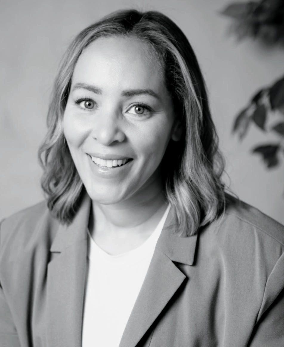 Black and white portrait of a smiling female behaviour therapist base in Toronto/EastYork with medium length hair and blazer.