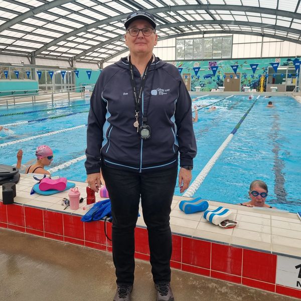 Swimming coach standing by an indoor pool.