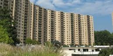 Large apartment building under a blue sky with greenery in the foreground.