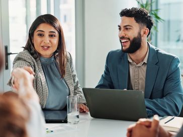 Two colleagues shaking hands across a table.
