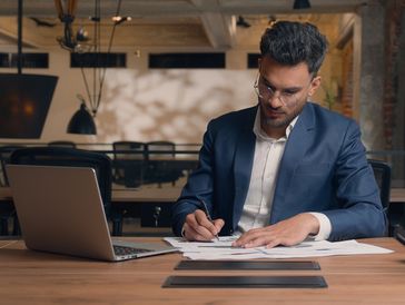 Man in a suit working on a laptop.