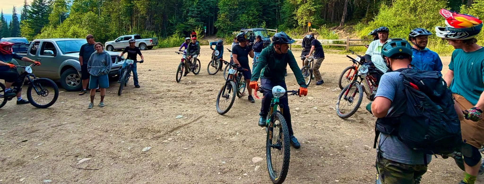 Group of mountain bikers gathering in a forest clearing.