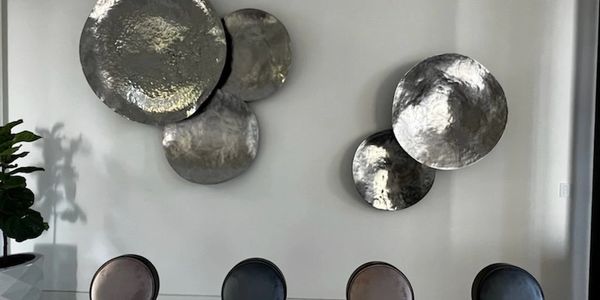 Modern dining room with metallic wall decor.