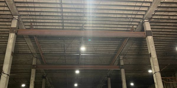 Metal beams and columns inside a large industrial building.