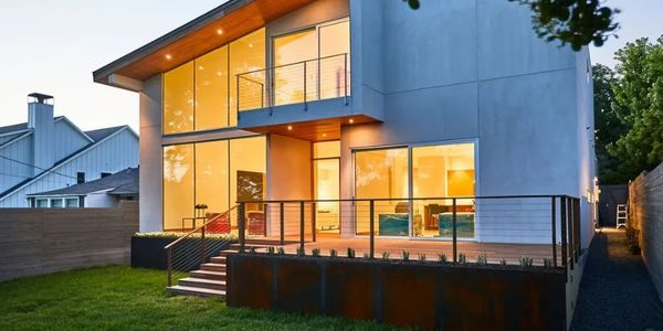 Modern house with large windows and a lit interior at dusk.