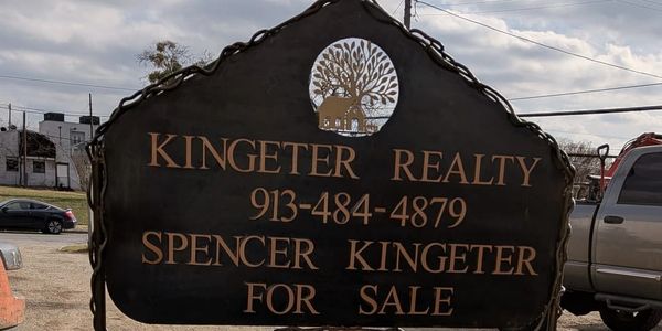 Rustic metal sign for Kingeter Realty with contact info.