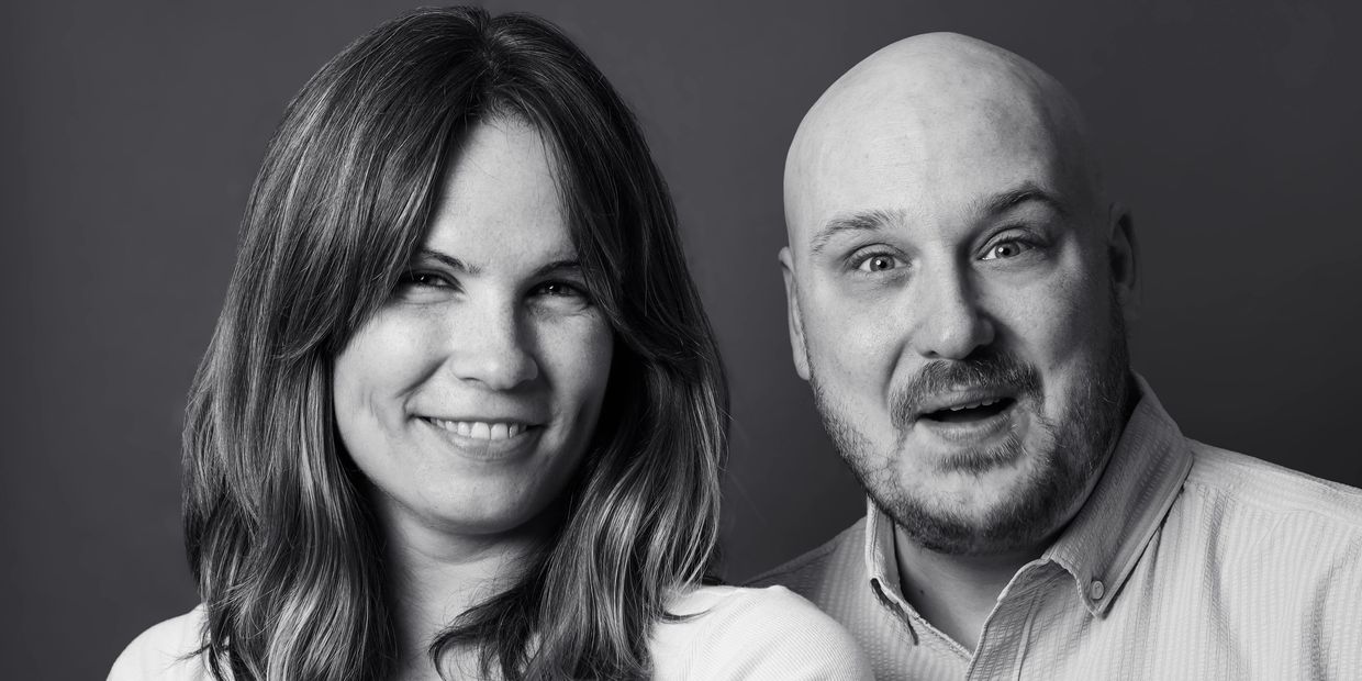 Smiling woman and surprised man in black and white portrait.