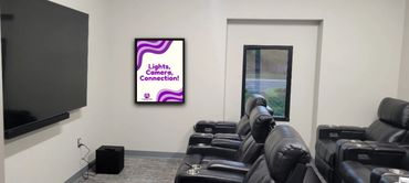 Modern home theater with black leather recliners and a motivational poster on the wall.
