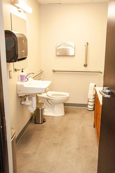 Clean and accessible restroom with grab bars and a hand soap dispenser.