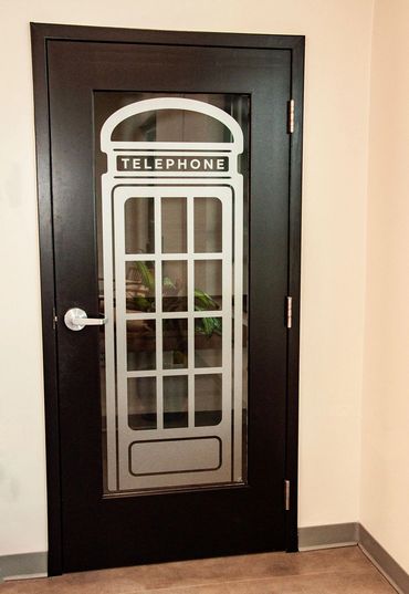 Black door with a frosted glass design of a classic telephone booth.