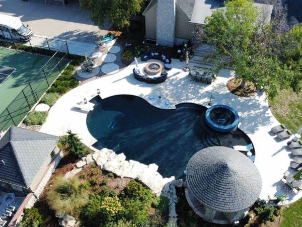 A uniquely shaped swimming pool with surrounding seating and landscaping.