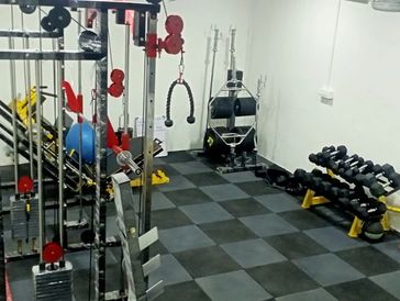 Compact home gym with various exercise equipment and dumbbells.