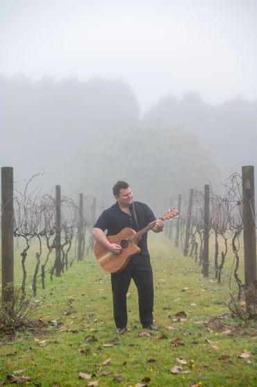 Musician posing amongst the vineyard at a winery wedding in Stanthorpe