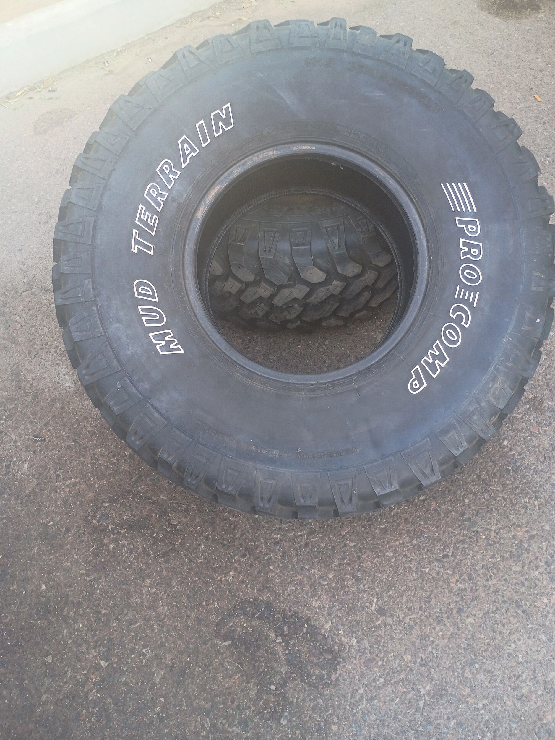 Close-up of a Pro Comp Mud Terrain tire on a rough surface.