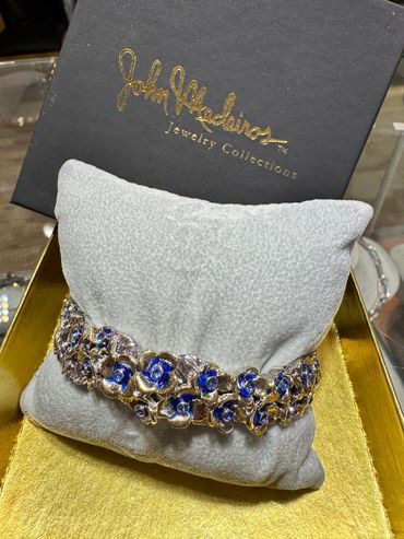 Elegant floral bracelet with blue accents on a soft cushion.