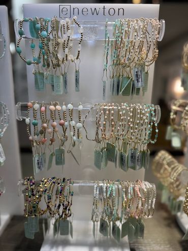 Display of colorful beaded bracelets on a three-tier acrylic stand.