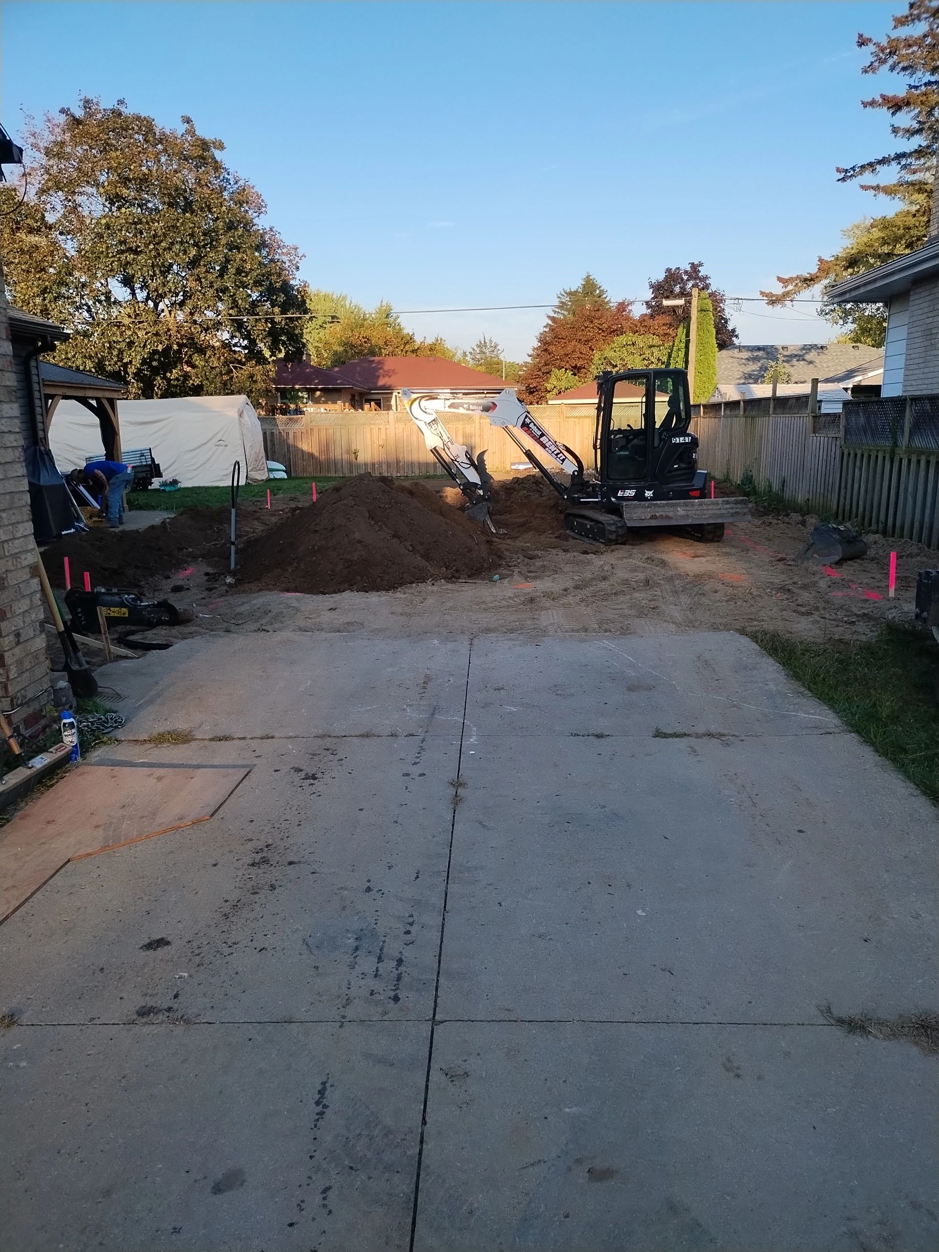 Construction site with excavator digging in a backyard for earthworks and excavation along with earth works construction.