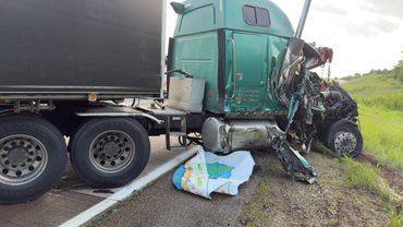 Damaged green semi-truck on roadside after an accident.