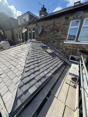 Slate roof repair work in progress on a brick house.