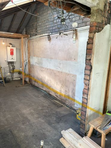 Interior of a room under renovation with exposed brick and wiring.