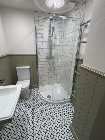 Modern bathroom with patterned floor tiles and glass shower enclosure.