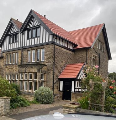 Traditional Tudor-style house with red roof and garden.